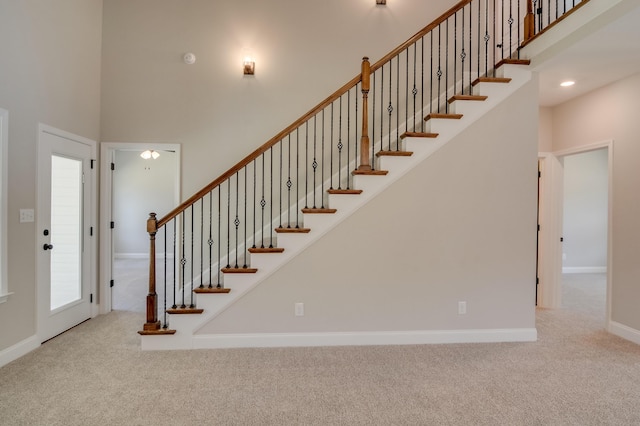 stairs featuring carpet flooring, a high ceiling, and plenty of natural light