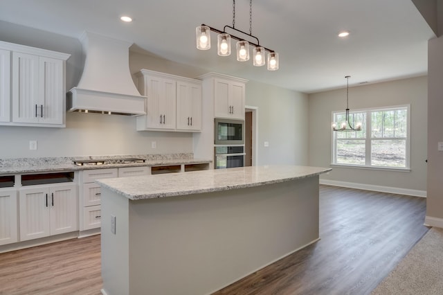 kitchen featuring white cabinetry, a center island, an inviting chandelier, premium range hood, and appliances with stainless steel finishes