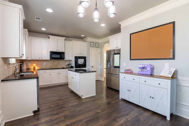 kitchen with a sink, arched walkways, black appliances, and dark countertops