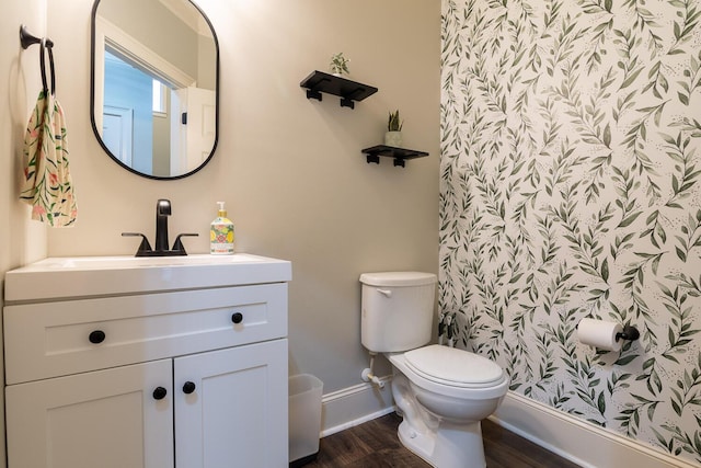 bathroom featuring toilet, baseboards, wood finished floors, and vanity