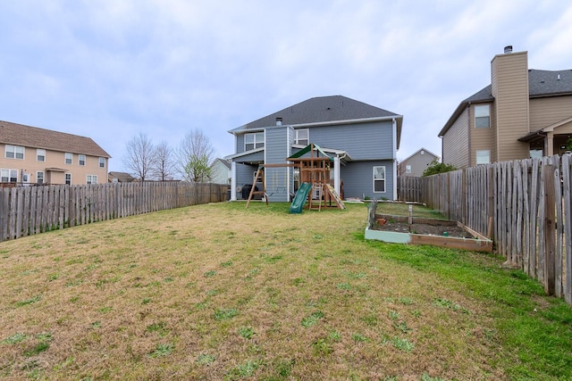 rear view of property with a playground, a lawn, a fenced backyard, and a vegetable garden