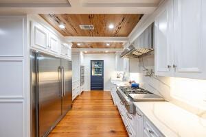 1792 Appleton Rd, Allendale, SC 29810 - kitchen featuring wall chimney range hood, light hardwood / wood-style flooring, appliances with stainless steel finishes, white cabinetry, and wood ceiling