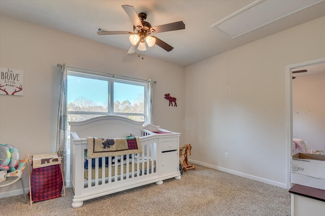 bedroom with a nursery area, light carpet, and ceiling fan