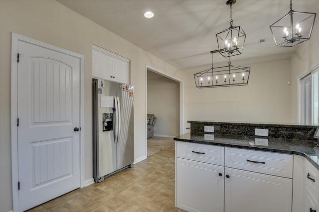 kitchen with dark stone counters, stainless steel fridge with ice dispenser, hanging light fixtures, and white cabinetry