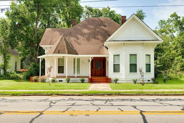 victorian house featuring covered porch and a front yard