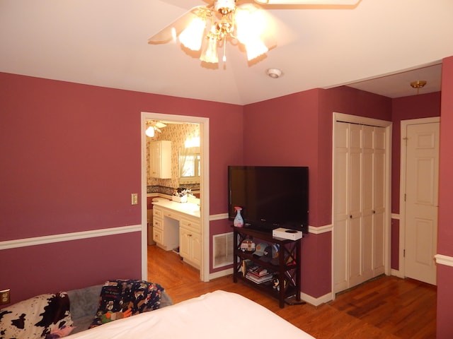 bedroom featuring hardwood / wood-style floors, ensuite bathroom, and ceiling fan