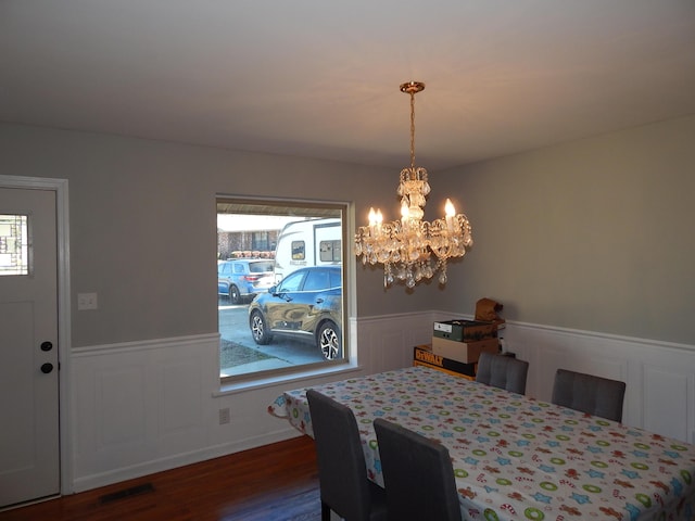 dining room with dark wood-type flooring, plenty of natural light, and a notable chandelier