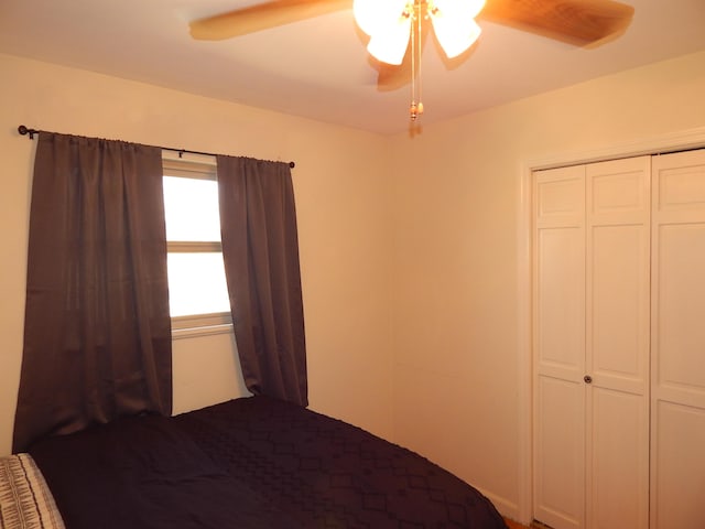 unfurnished bedroom with ceiling fan and a closet