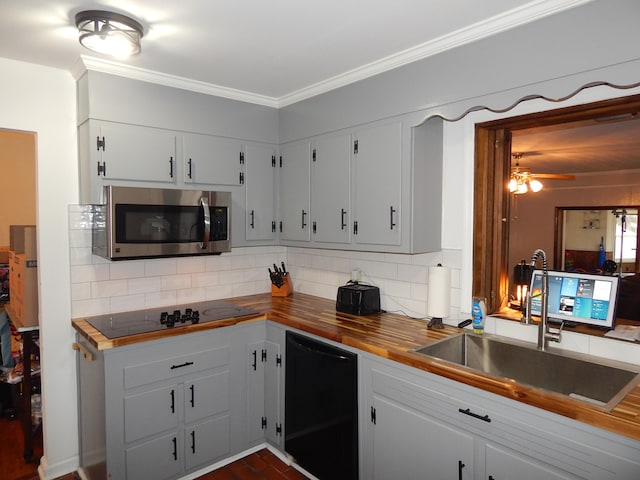 kitchen with wood counters, black appliances, white cabinets, sink, and tasteful backsplash