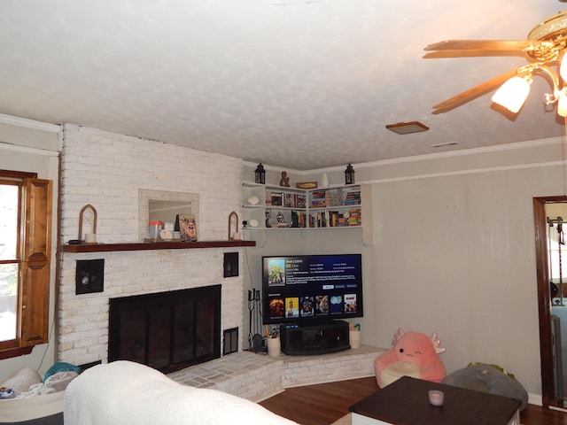 living room featuring ceiling fan, a fireplace, wood-type flooring, and ornamental molding