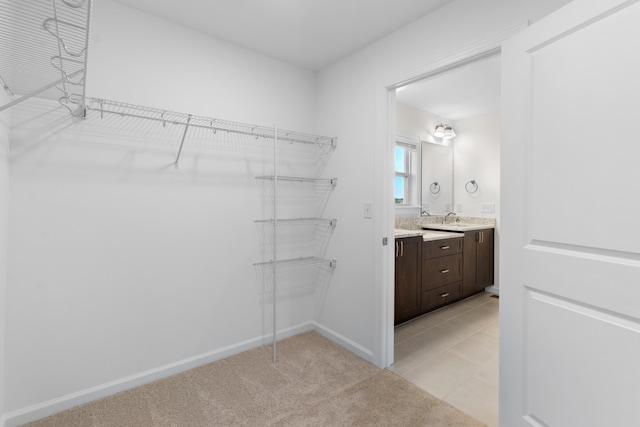 walk in closet with light carpet and sink