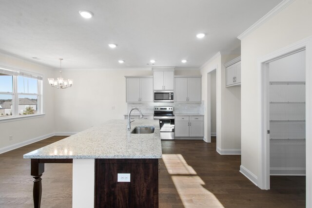 kitchen with light stone countertops, appliances with stainless steel finishes, tasteful backsplash, sink, and a center island with sink