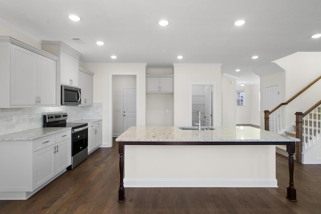 kitchen with light stone countertops, sink, stainless steel appliances, and an island with sink