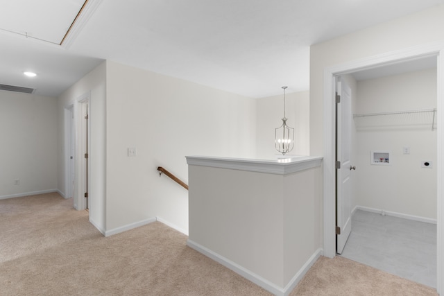 hallway with an inviting chandelier and light colored carpet