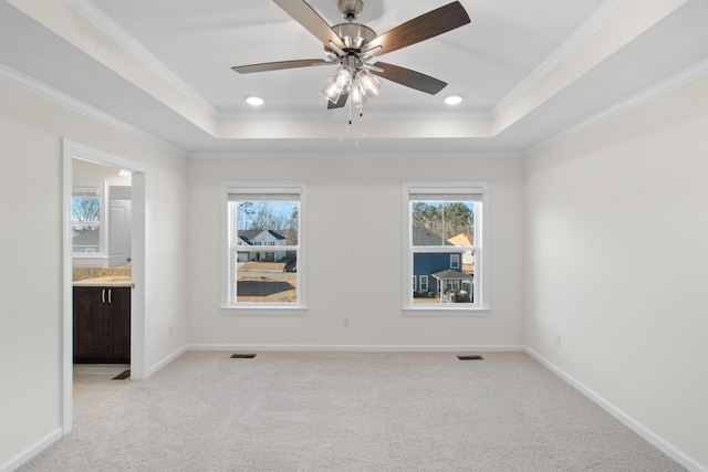 empty room featuring crown molding, light colored carpet, and a tray ceiling