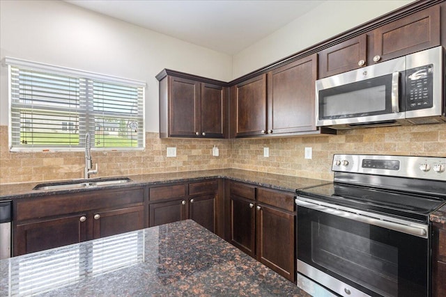 kitchen with sink, stainless steel appliances, and dark stone counters