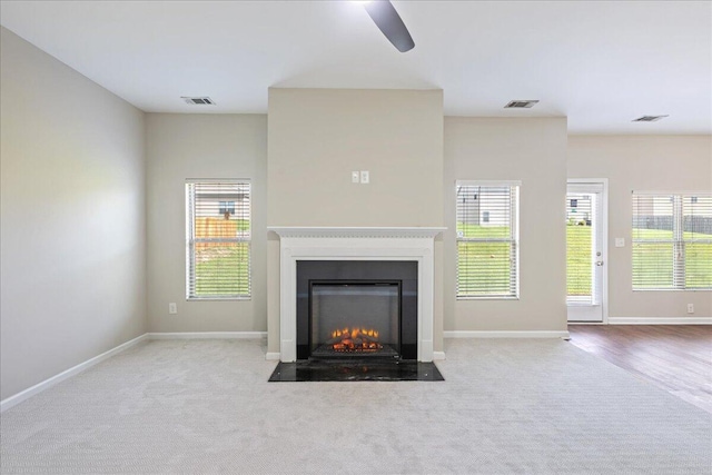 unfurnished living room featuring ceiling fan and light carpet