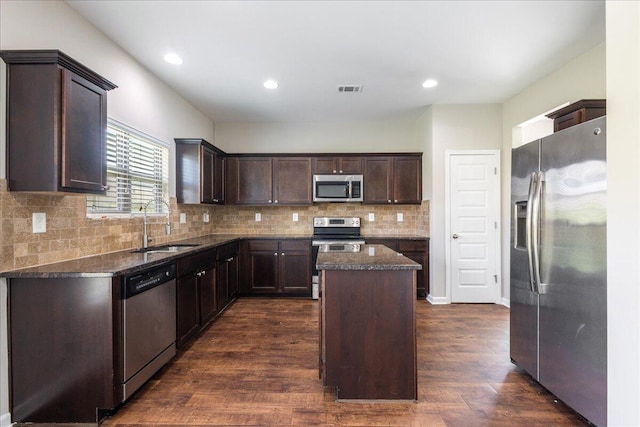 kitchen with dark wood-type flooring, sink, appliances with stainless steel finishes, dark brown cabinets, and a kitchen island