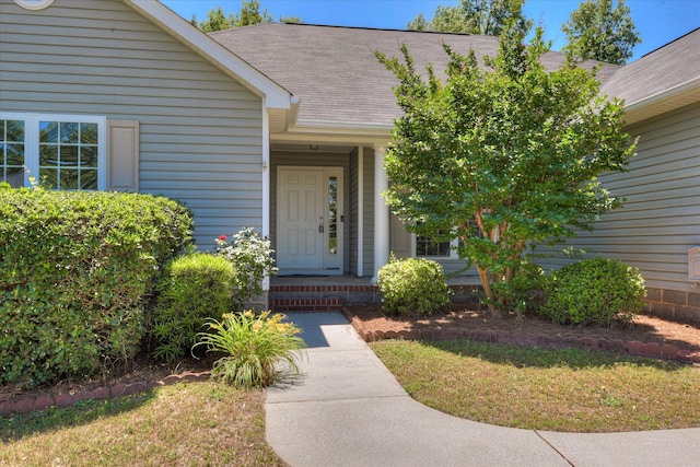 doorway to property featuring a shingled roof and a yard