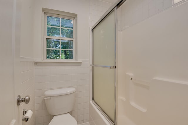 full bath featuring tile walls, toilet, and bath / shower combo with glass door