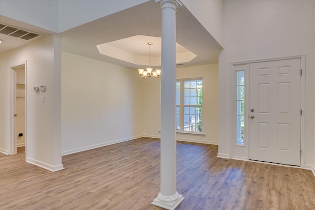 foyer with baseboards, wood finished floors, a chandelier, and a raised ceiling