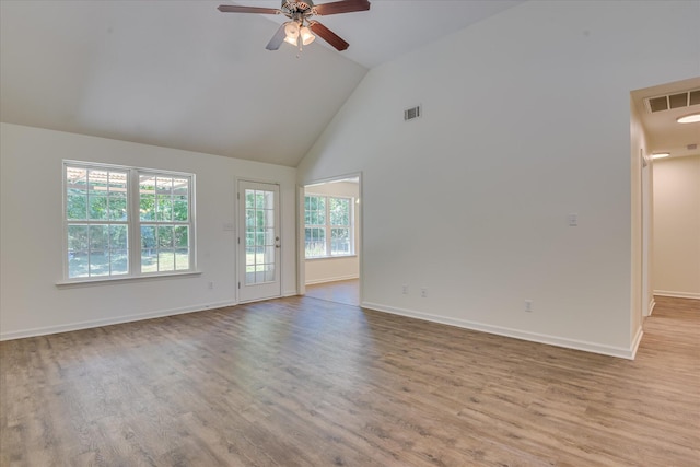 empty room with wood finished floors, ceiling fan, high vaulted ceiling, and baseboards
