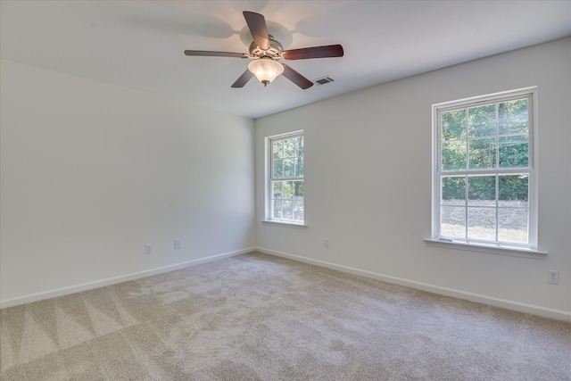spare room featuring light colored carpet, baseboards, and ceiling fan