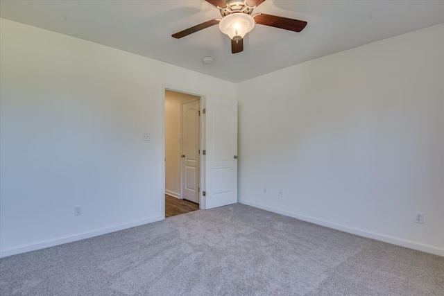 unfurnished room featuring dark colored carpet, a ceiling fan, and baseboards