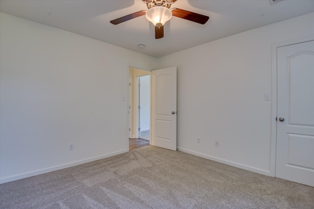 carpeted spare room with ceiling fan and baseboards