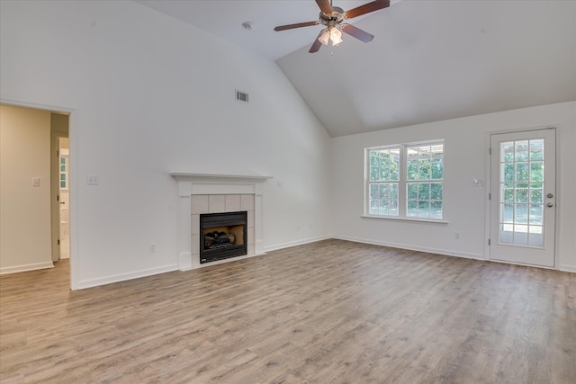 unfurnished living room featuring wood finished floors, high vaulted ceiling, ceiling fan, a tiled fireplace, and baseboards