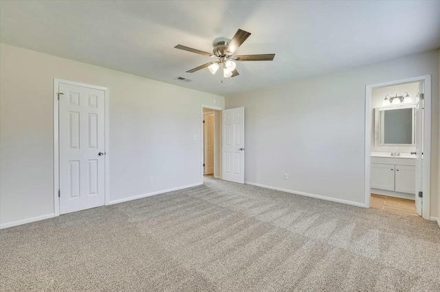 unfurnished bedroom featuring light carpet, connected bathroom, and ceiling fan