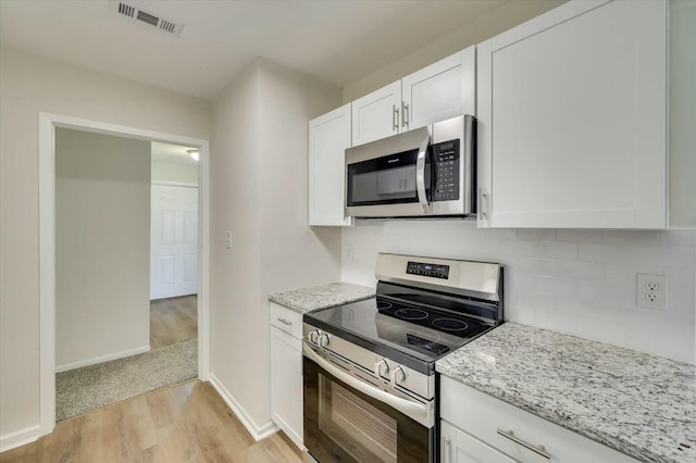 kitchen featuring white cabinets, light hardwood / wood-style floors, light stone countertops, and appliances with stainless steel finishes