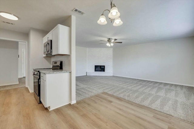 kitchen with a fireplace, stainless steel appliances, ceiling fan, pendant lighting, and white cabinets