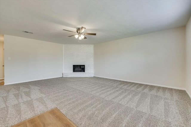 unfurnished living room featuring carpet flooring, a brick fireplace, and ceiling fan