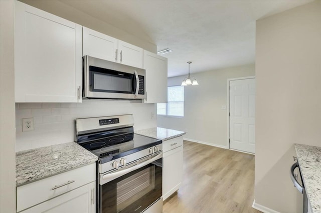 kitchen featuring white cabinets, decorative light fixtures, stainless steel appliances, and light stone countertops