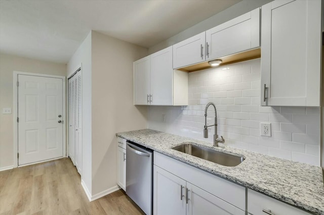 kitchen with tasteful backsplash, stainless steel dishwasher, white cabinetry, and sink