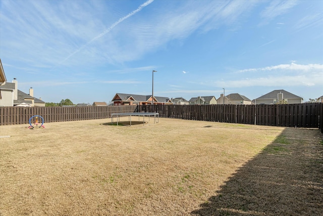 view of yard featuring a trampoline and a fenced backyard