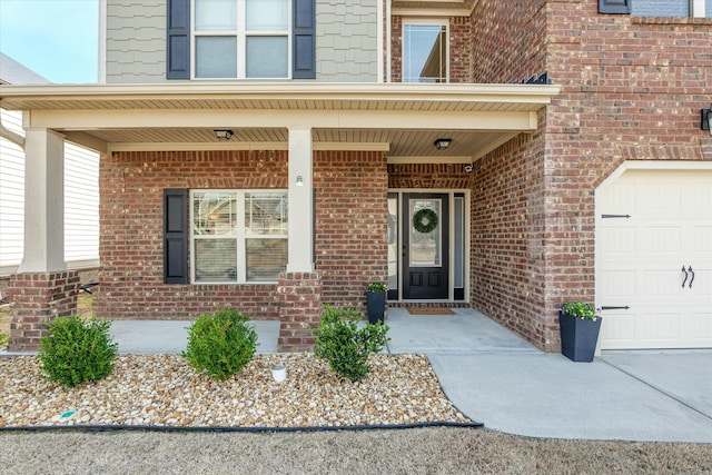 doorway to property with an attached garage, a porch, and brick siding