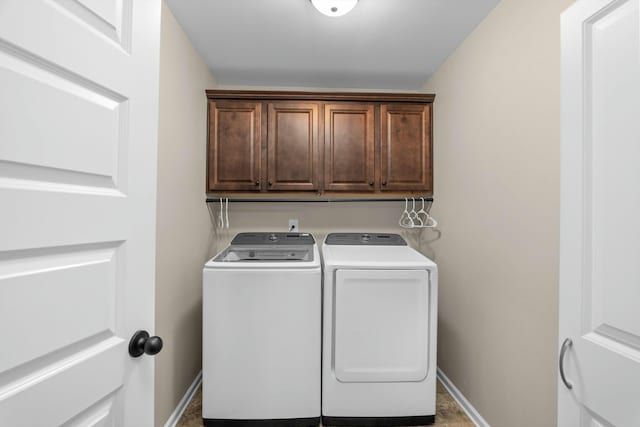 laundry area featuring washing machine and dryer, cabinet space, and baseboards