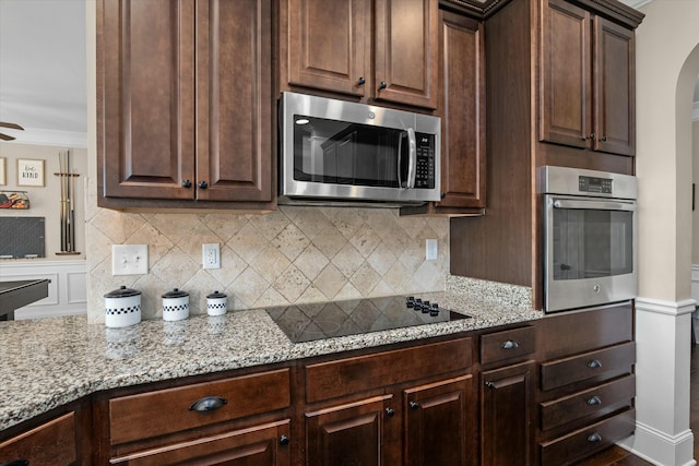 kitchen featuring crown molding, light stone counters, stainless steel appliances, and decorative backsplash