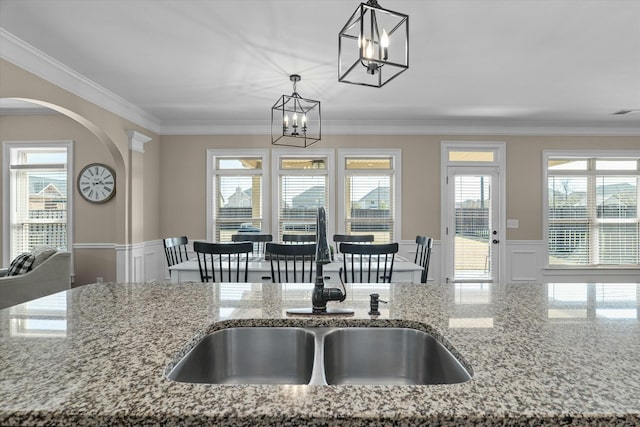 kitchen featuring ornamental molding, wainscoting, granite finish floor, and a decorative wall