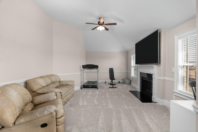 carpeted living area with a fireplace with flush hearth, lofted ceiling, plenty of natural light, and baseboards