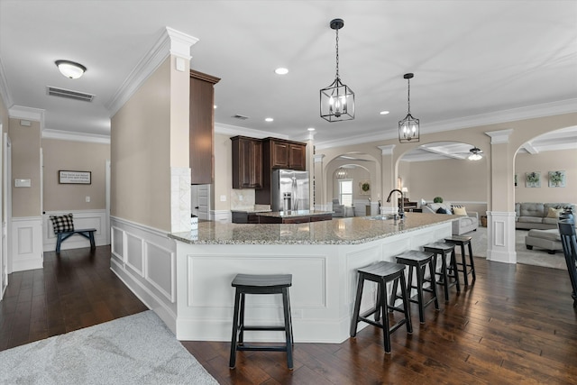 kitchen featuring arched walkways, open floor plan, stainless steel refrigerator with ice dispenser, and visible vents