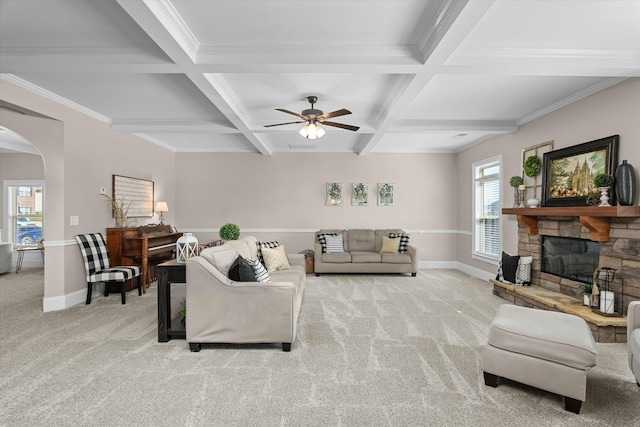 living room with arched walkways, beam ceiling, light colored carpet, a stone fireplace, and coffered ceiling