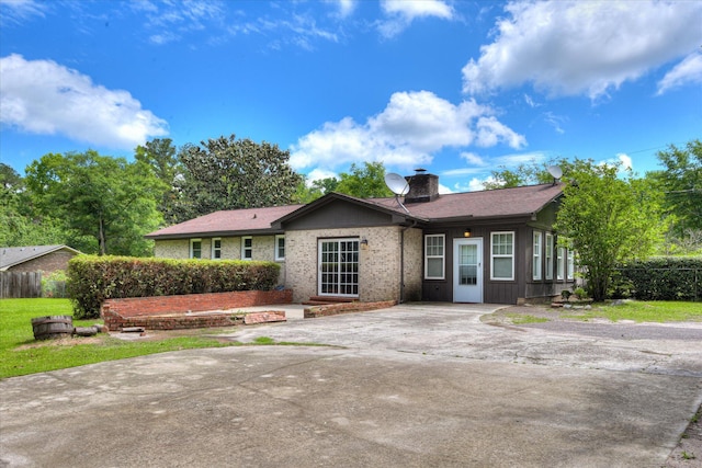 ranch-style home featuring a chimney, driveway, and fence