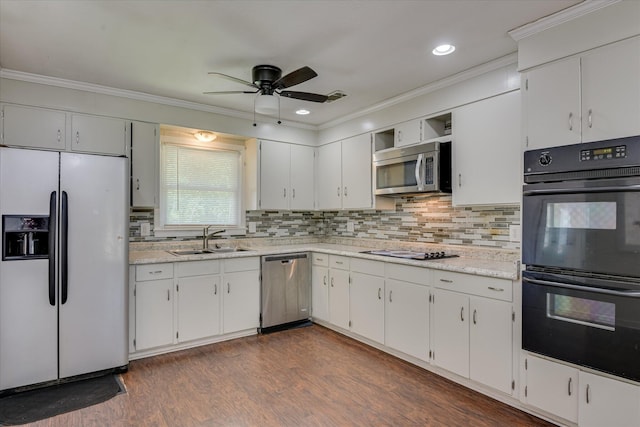 kitchen with appliances with stainless steel finishes, a sink, ceiling fan, crown molding, and decorative backsplash