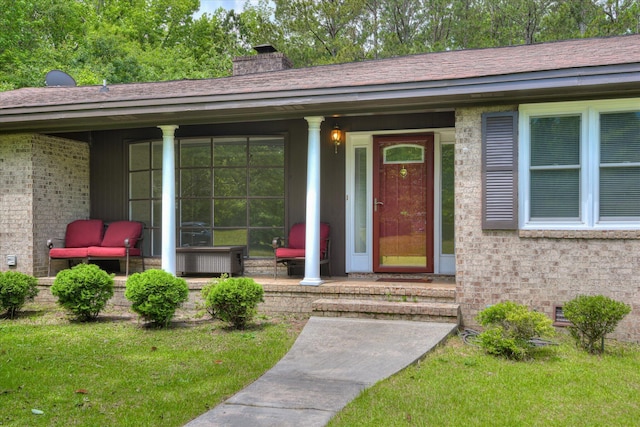 property entrance featuring a chimney, covered porch, and brick siding