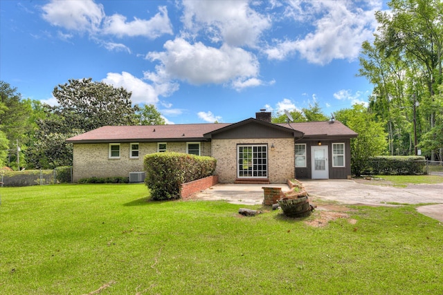 view of front of house with central AC unit, a chimney, brick siding, and a patio