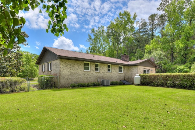 rear view of house with brick siding, central air condition unit, a gate, a chimney, and crawl space