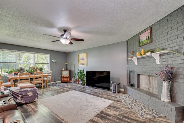 2382 Patrick Ave, Hephzibah, GA 30815 - living room with wood finished floors, a ceiling fan, a textured ceiling, a brick fireplace, and baseboards
